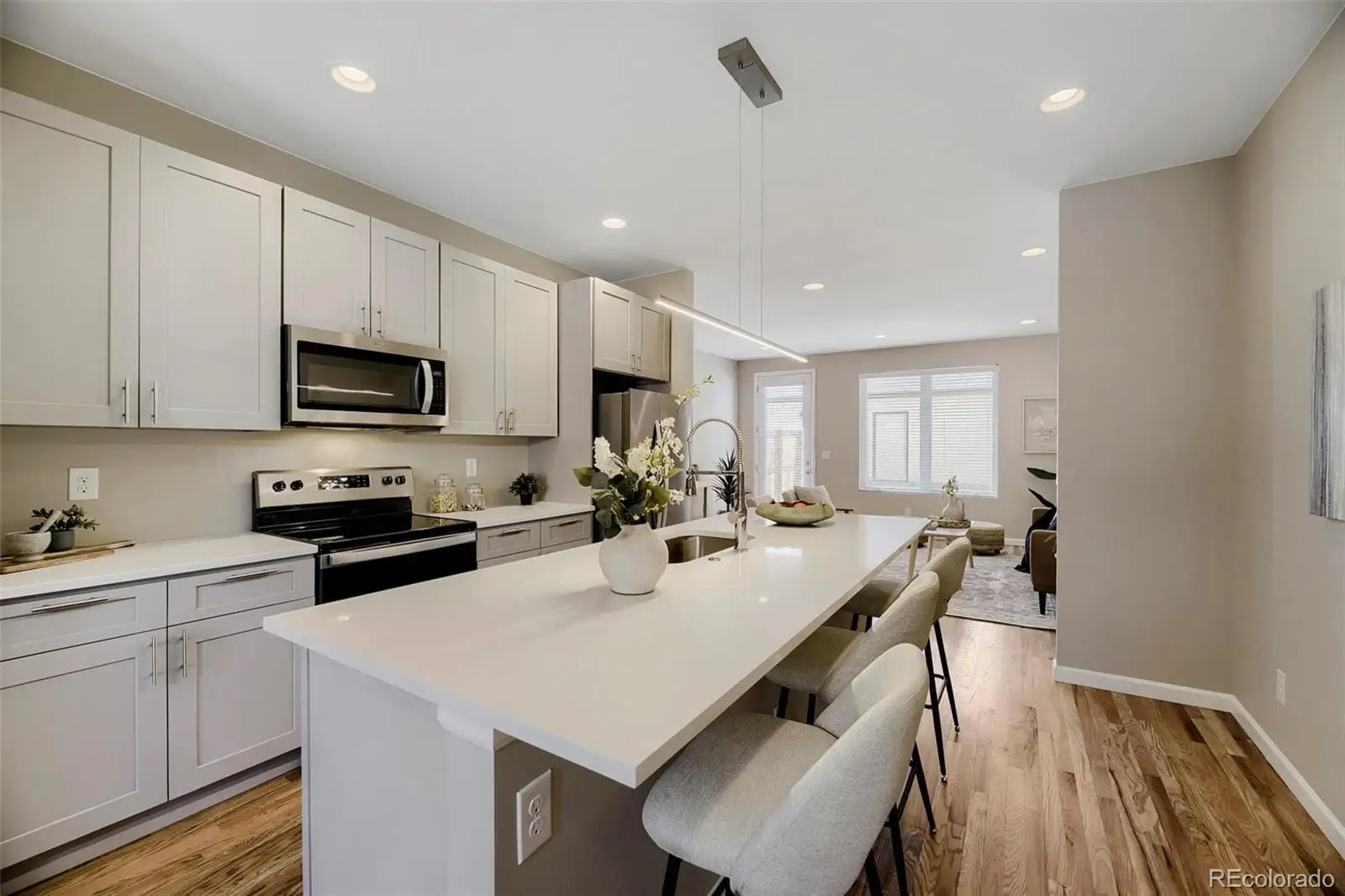 A kitchen with a sink a stove a refrigerator and white cabinets with wooden floor at 1027 Julian Street