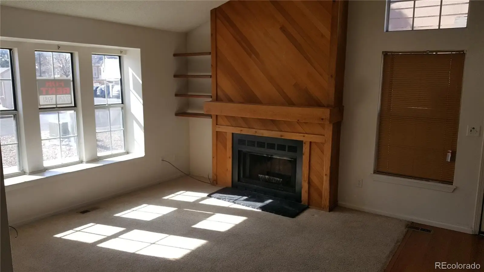 A view of an empty room with a fireplace and a window at 17155 East Chenango Avenue, Unit A
