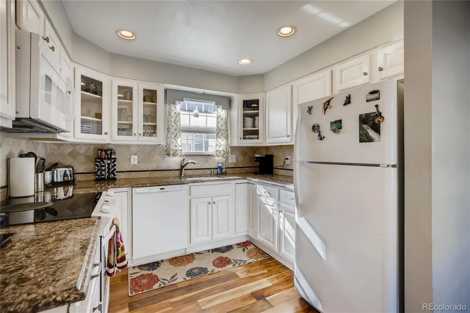 A kitchen with granite countertop a refrigerator and a sink at 7553 West Euclid Drive