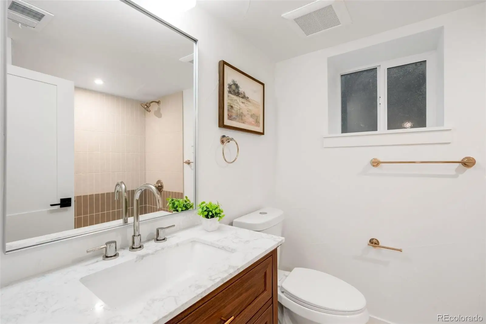 A bathroom with a sink vanity mirror and toilet at 2343 Dahlia Street